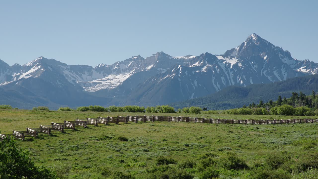 montañas de san juan con una valla de madera y tierras de cultivo en primer plano