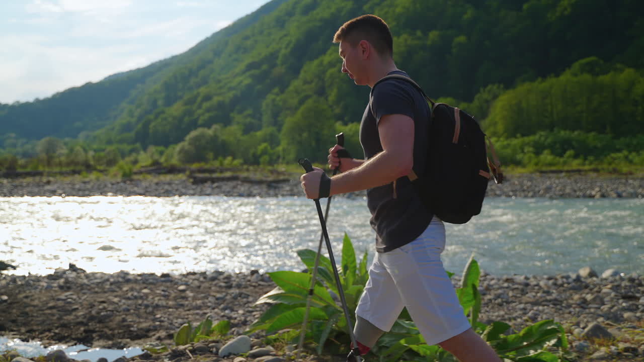 hombre caminando en las montañas por el río con una pierna protésica