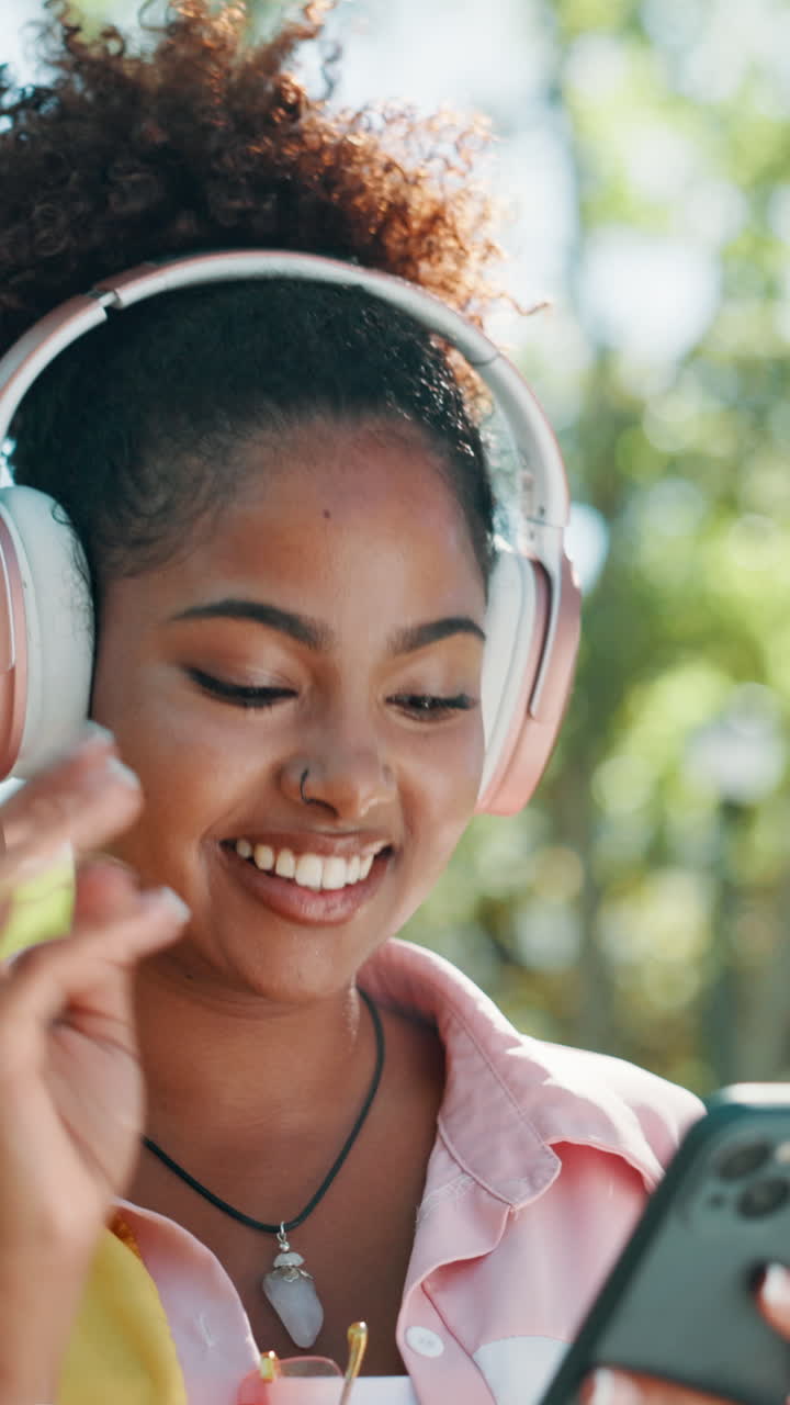 Giovane donna felice che ascolta musica in cuffia all'aperto.
