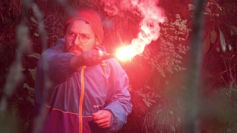 man with red flare in the forest at night