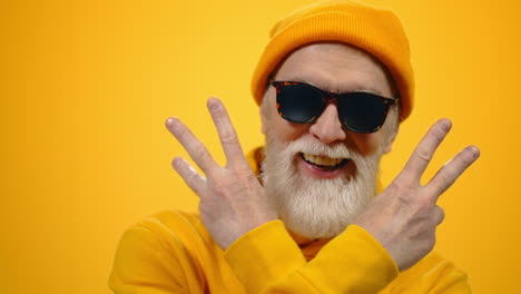 cheerful old man raising hands indoors. joyful guy posing to camera in studio.