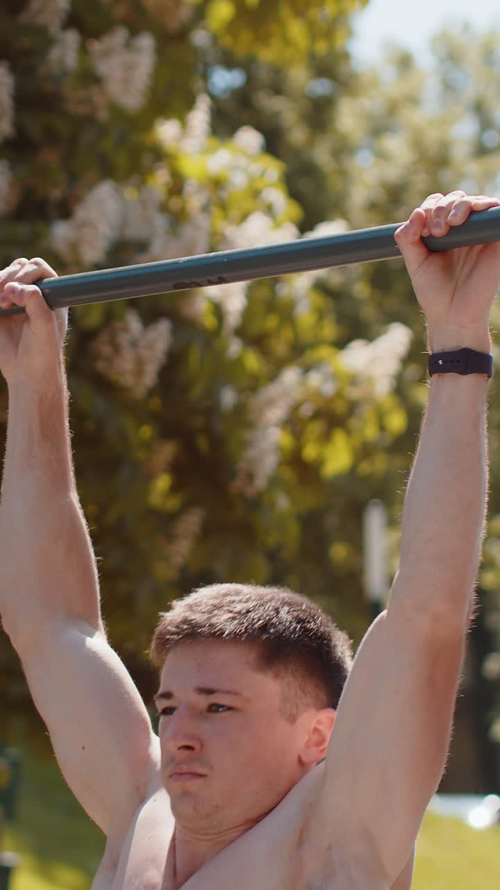 Athletic caucasian topless muscular man doing pull ups exercises on horizontal bar pumping up back
