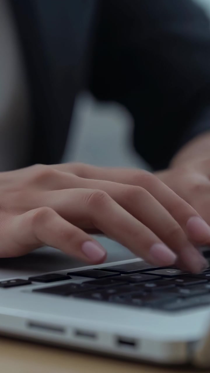 Video verticale: Mani sospese che indossano un blazer e iniziano a digitare per lavoro alla scrivania dell'ufficio, usando un laptop