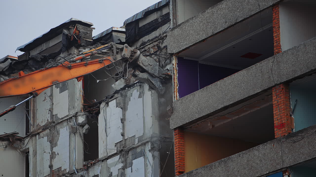 Bulldozer claw grab the concrete wall in order to break it. Demolishing the building wrecked by an earthquake. View from below.