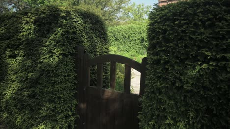 pullback over a wooden garden gate hiding away a secret garden