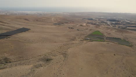 Countryside-of-Lanzarote,-Canary-Islands,-Spain,-Aerial-View-of-Dry-Landscape-and-Small-Farming-Fields,-Drone-Shot