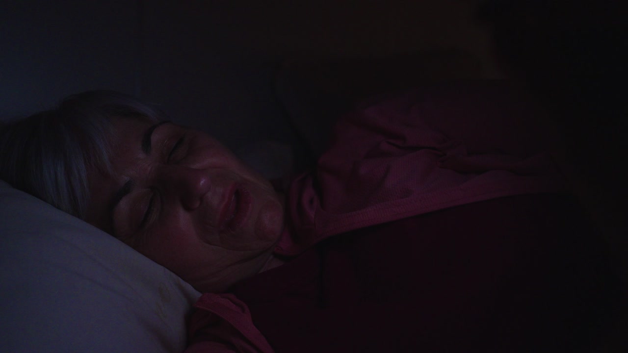 Mulher Idosa Bocejando e se Espreguiçando na Cama à Noite