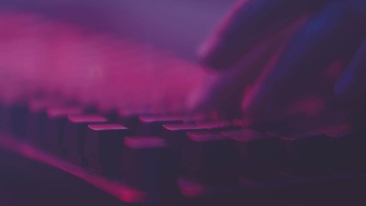 Hands Typing on a Keyboard Under Neon Lights