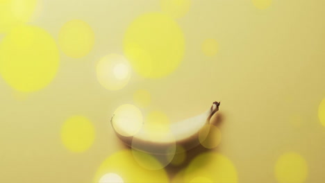 composition of spots of light over banana on yellow background