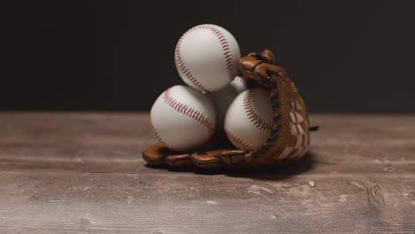 baseball still life with person picking up ball from catchers mitt on wooden floor 1