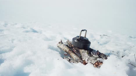 man putting twigs on fire to boil the water on kettle