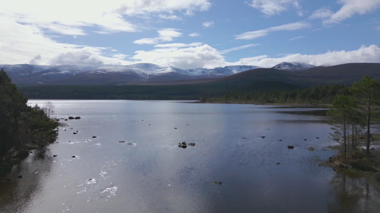 vuelo aéreo sobre las aguas del lago morlich revelando las montañas cairngorms, escocia
