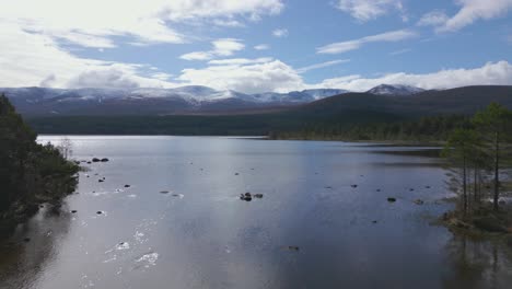 aerial flying over waters of loch morlich revealing cairngorms mountains, scotland