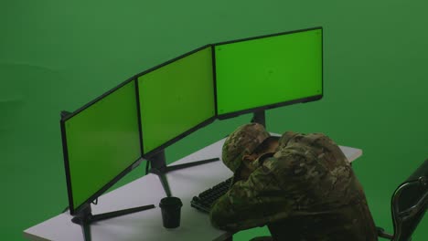 side view of tired asian man soldier sleeping while working with mock up multiple computer monitor in green screen studio