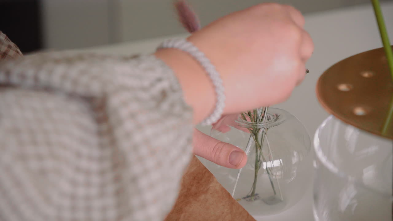 말린 꽃으로 꽃병을 장식하는 젊은 여성, 집 안의 탁자에 있는 꽃다발은 4k 가까이