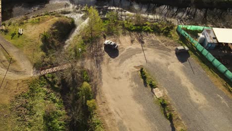 Aerial-track-shot-of-person-running-over-bridge-and-getting-into-car-during-sun