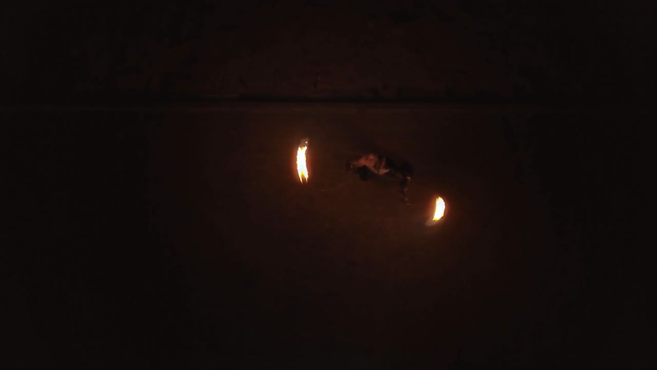 un joven macho aéreo hace trucos con fuego gira dos antorchas ardientes