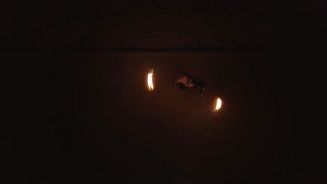 aerial young male does tricks with fire spins two burning torches