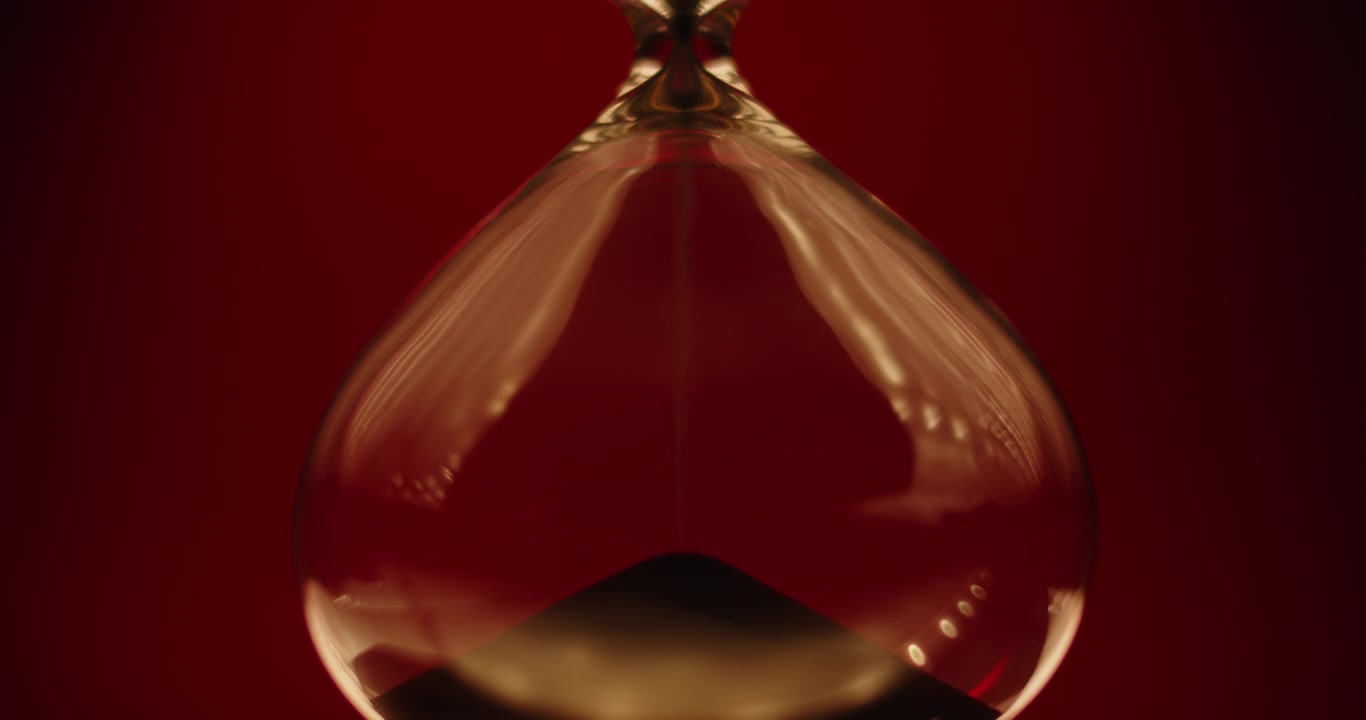 Black sand pouring inside of sand clock