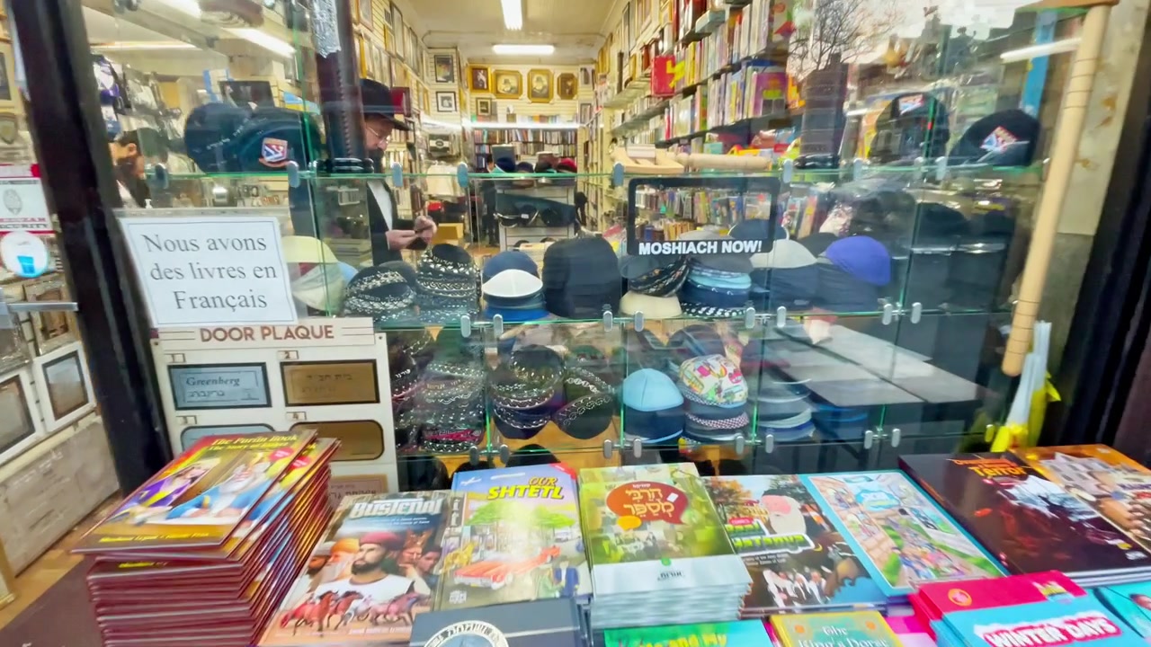 New York, AS, 9 Maret 2022: Fasad toko buku Yahudi dengan meja pajangan di trotoar New York. Pemandangan jalan sebuah toko buku Yahudi kecil di New York.