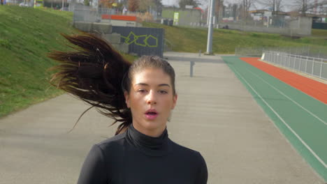 primer plano de una hermosa chica deportiva corriendo, fuera de casa, tiro frontal