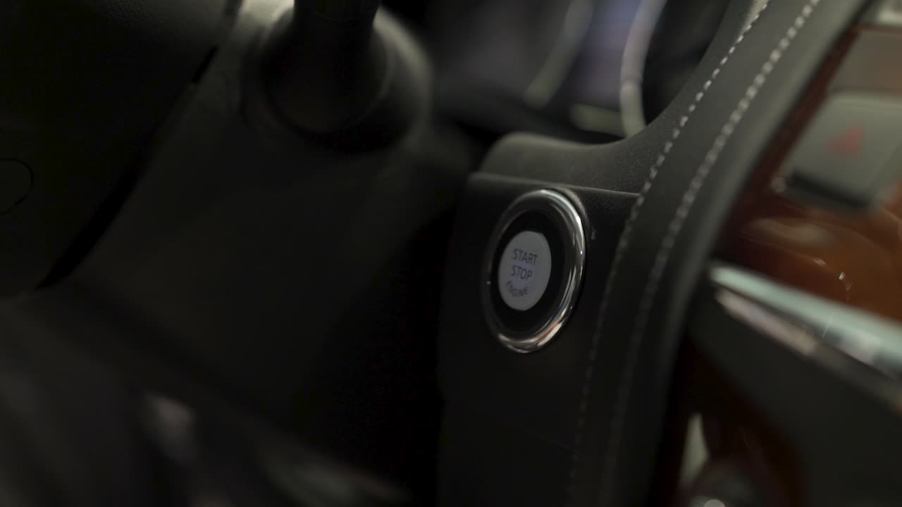 persona presionando un botón de arranque del coche