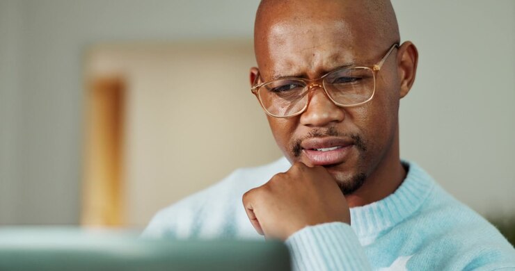 Focused Man Wearing Glasses Looking at Laptop Screen