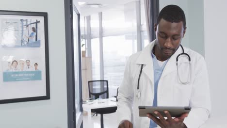 African-american-male-doctor-using-tablet-in-hospital,-slow-motion