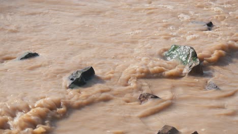 Close-Shot-of-Murky-Water-and-Rocks-at-the-Lake-Shore