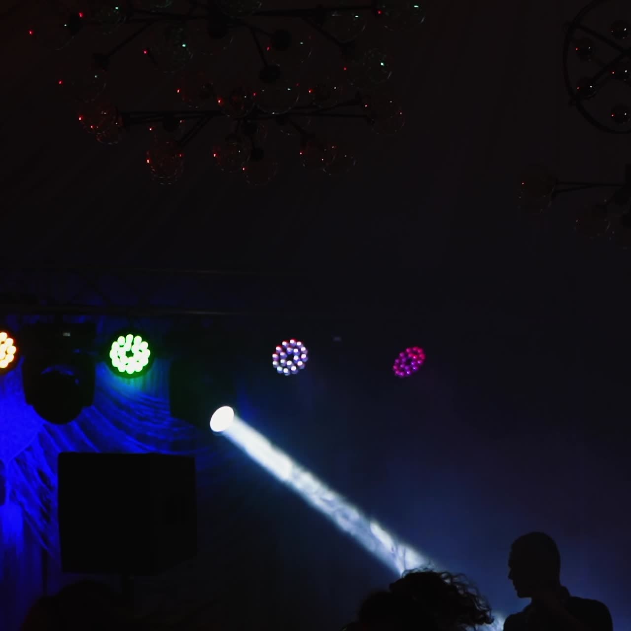 Disco party indoors. Colorful lights from projectors shimmering in the dancing hall. People having fun in night club.