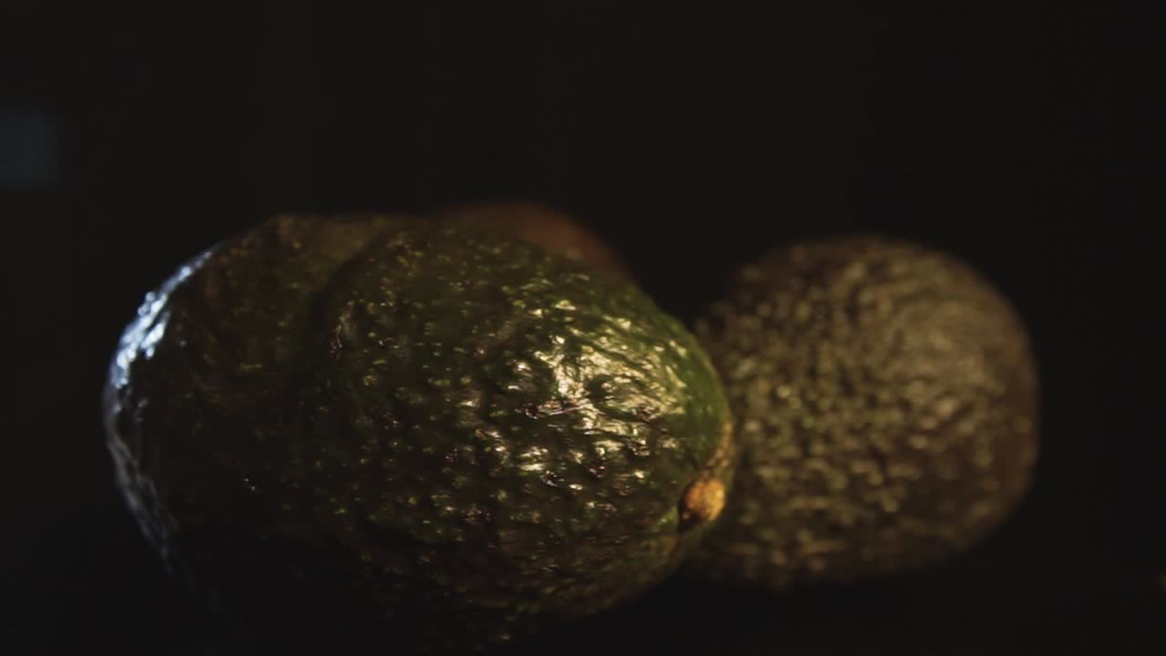 Macro shot of slow rotating avocados with black background lighted in Professional studio