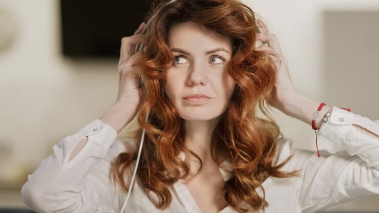 Donna felice che indossa gli auricolari in soggiorno.