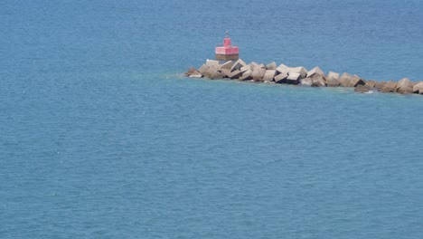 A-single-fishing-boat-sails-past-a-stone-quay-entering-the-harbor