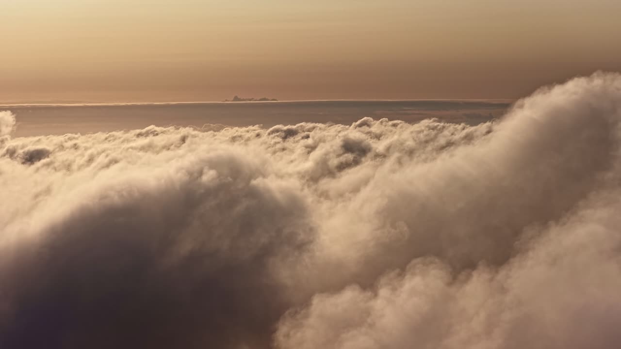 Impresionantes imágenes aéreas sobrevolando un denso y ondulado manto de nubes durante la cálida hora dorada.