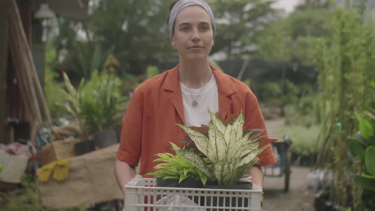 Female Plant Nursery Worker Walking with Plants in Crate