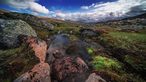 Un-Vídeo-Timelapse-Captura-El-Reflejo-De-Las-Nubes-Tormentosas-Y-El-árido-Paisaje-Nórdico-En-La-Superficie-Similar-A-Un-Espejo-De-Un-Pequeño-Estanque.