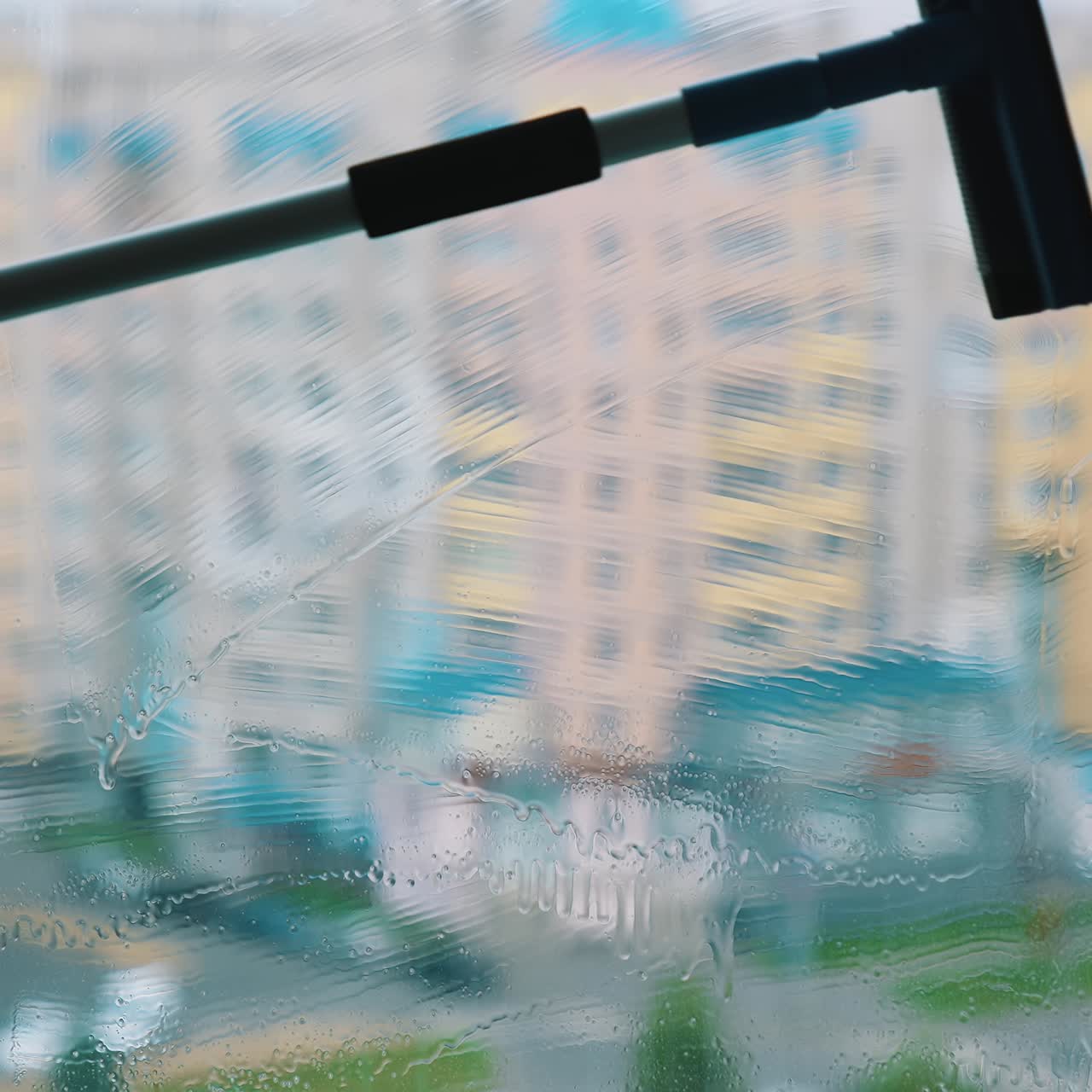 Brush cleaning dirty window with water and soap. Washing glass window inside on city building background