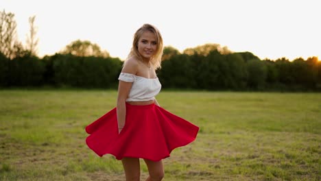 beautiful blond girl twirling in a red dress during a golden hour sunset