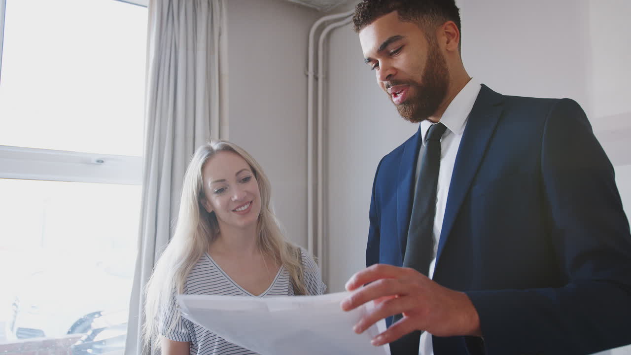 Female First Time Buyer Looking At House Survey With Realtor