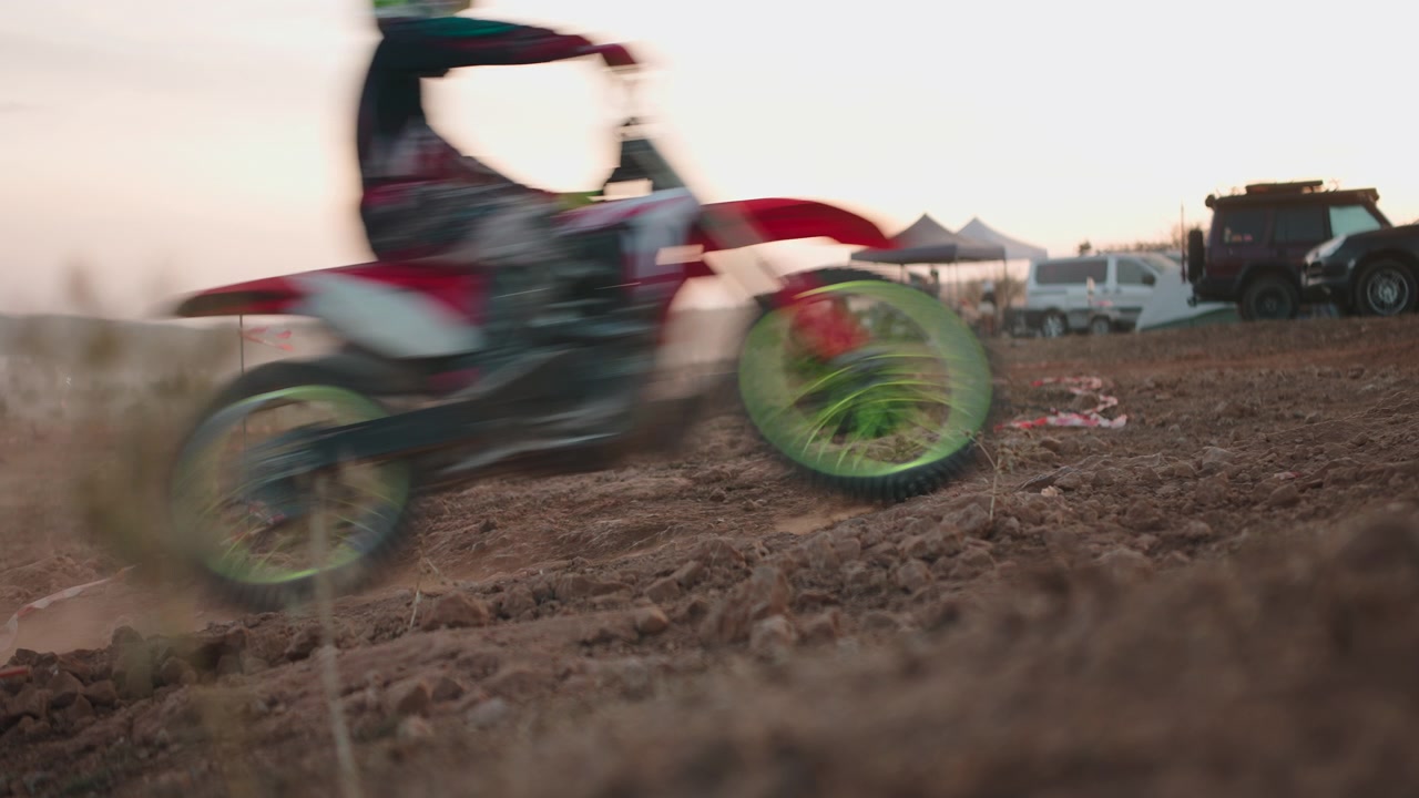 Piloto de motocross correndo em pista de terra ao pôr do sol