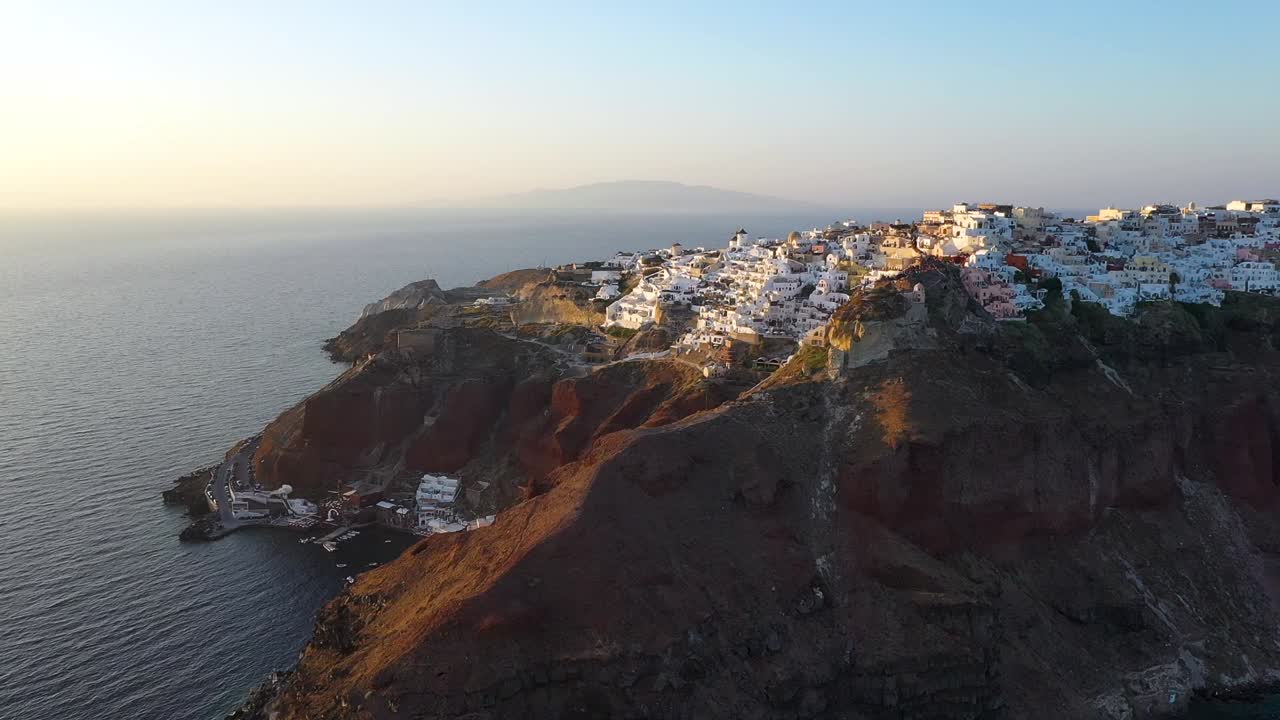 video de drones del famoso pueblo pintoresco encalado y colorido de oia construido sobre un acantilado durante la puesta de sol, isla de santorini, cícladas, grecia