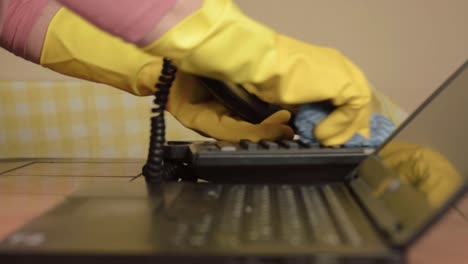 hands in rubber gloves cleaning office phone with cloth