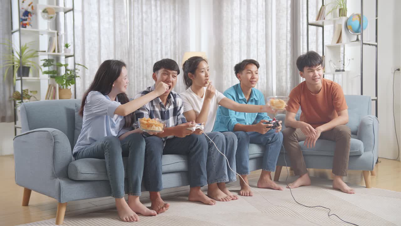 친구들이 비디오 게임을 하고 간식을 먹고 있습니다.