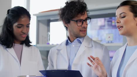 International-Group-of-Scientists-in-Laboratory.science-research,-work-and-people-concept-international-group-of-happy-scientists-with-clipboards-discussing-report-in-laboratory