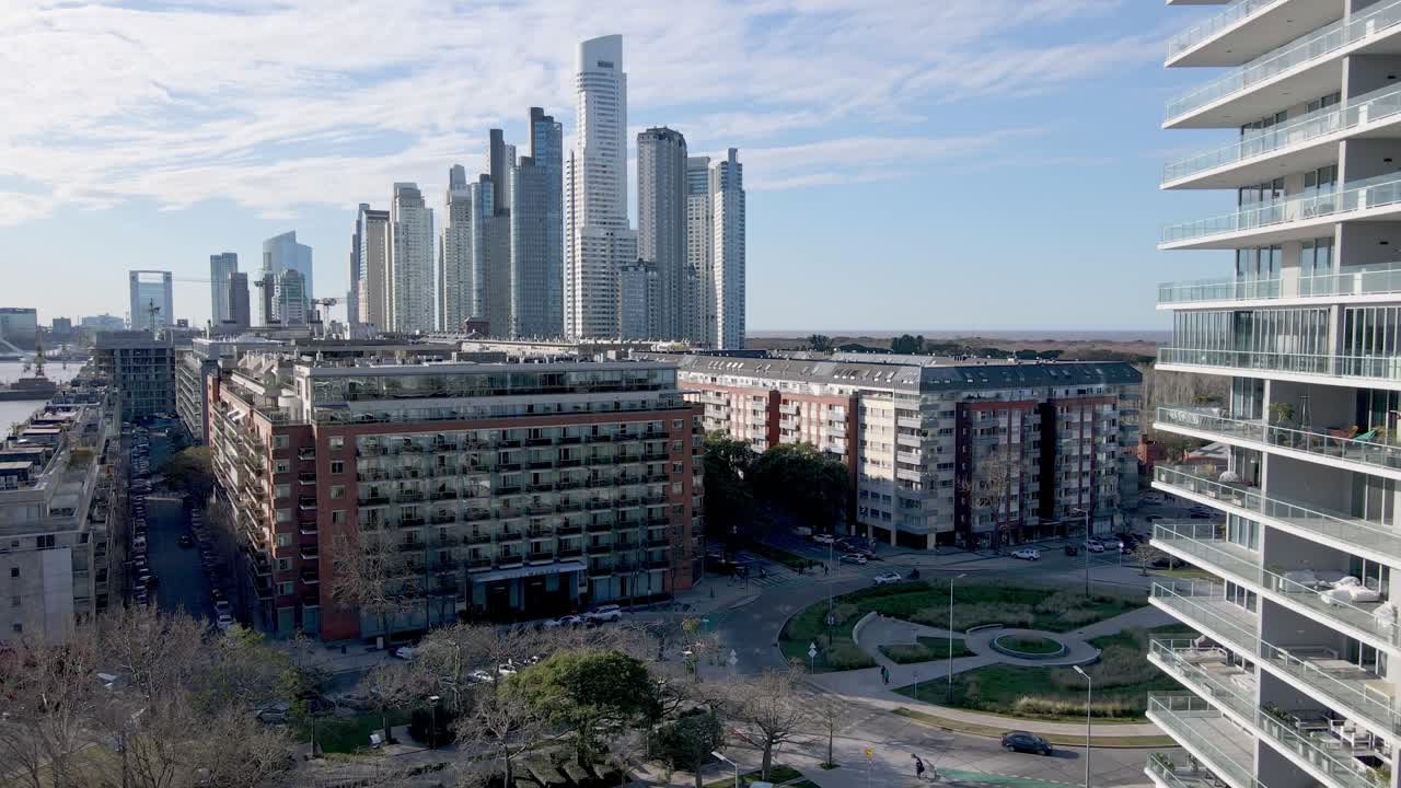 Ripresa aerea all'indietro che mostra una zona residenziale e l'enorme skyline di Buenos Aires sullo sfondo.