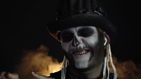 creepy man with skeleton makeup in top-hat. guy wearing earphones, listening music, dancing