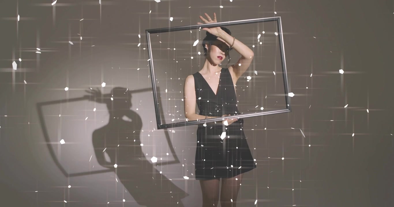 Modello che solleva e ruota una cornice sopra la testa, mentre una proiezione stellare modella un'ombra in uno studio cinematografico.