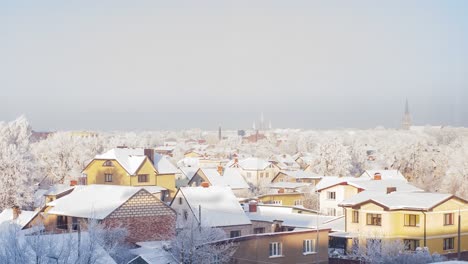 Beautiful-timelapse-view-of-Liepaja-city-cityscape,-private-residential-buildings-covered-in-snow,-smoke-from-chimneys,-sunny-winter-day,-wide-angle-shot