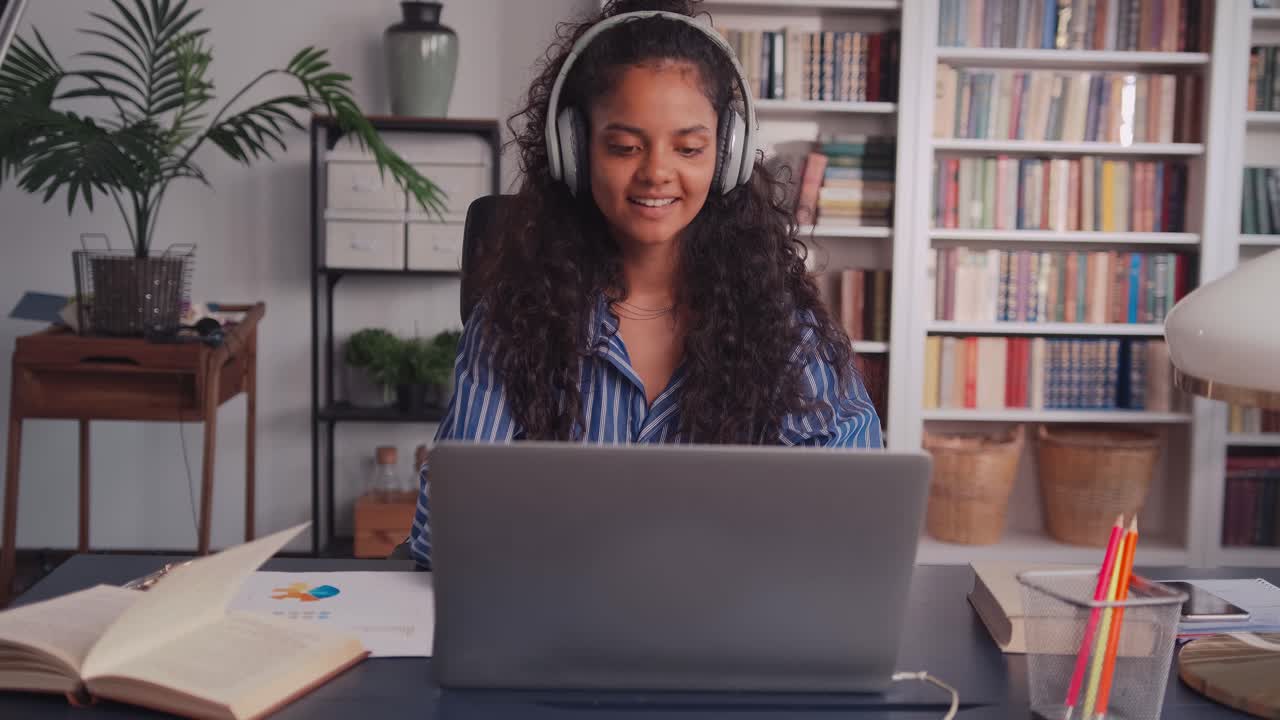 Smart indian student putting headphones browsing school ideasc on laptop
