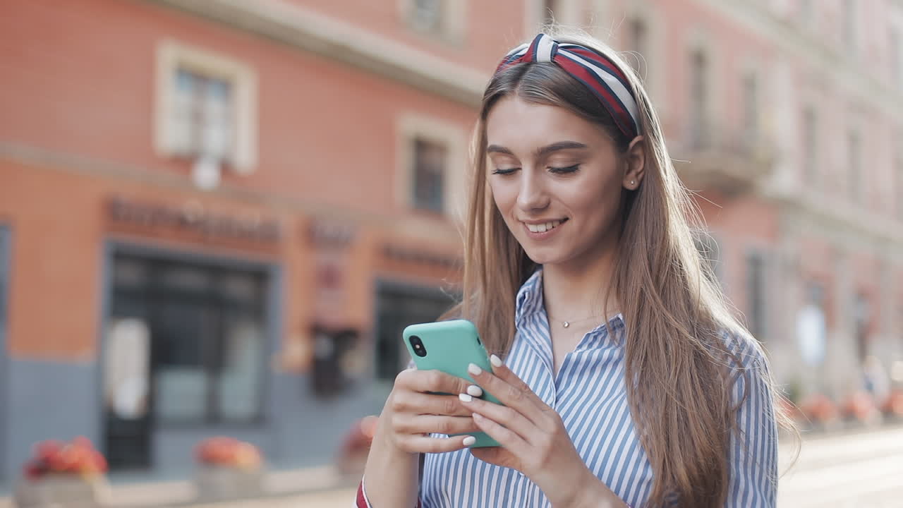 Jovem Feliz Sorrindo Enquanto Usa Smartphone na Rua da Cidade.
